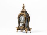 une petite horloge posée sur une surface blanche