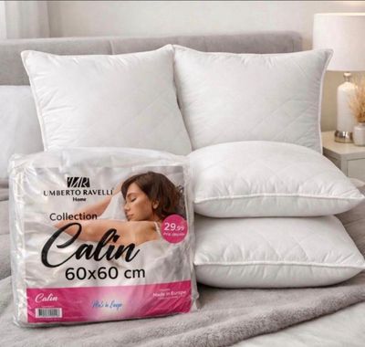 two pillows on a bed with a pillow on top of it