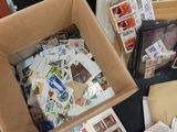 a box full of stamps sitting on the floor next to a pile of books