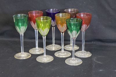 Plusieurs verres à vin de différentes couleurs sont alignés sur une surface noire