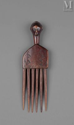 un peigne en bois sur lequel est représenté un visage