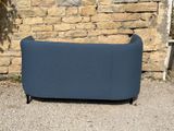 a blue couch sitting in front of a stone wall