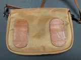 brown and tan purse with two leather handles on a gray surface
