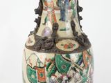 un vase blanc orné d'une peinture et sur lequel est posée une lampe