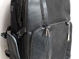 un sac à dos noir posé contre un mur blanc