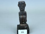 une petite statue en bois représentant un homme assis sur un socle noir