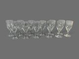 six verres à vin en cristal alignés sur une surface grise