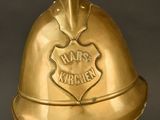 brass fireman ' s helmet on a clear stand with a black background