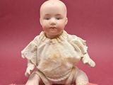 a small doll that is sitting on a pink surface