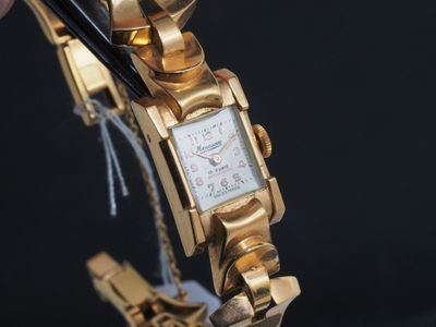 une personne tenant une montre-bracelet en or et une paire de ciseaux