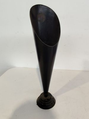 un vase noir posé sur une table blanche, sur fond blanc