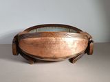 a large copper bowl on a stand on a table