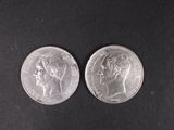two silver coins, one with the head of a woman and one with a man ' s head