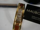 a gold watch with a brown band on a white table