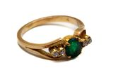 une image d'un gros plan d'une bague en or avec une pierre verte