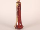 a red and white vase sitting on a white surface