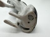 a figurine of a dog laying down on a white surface