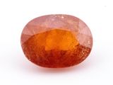 un gros plan d'un saphir orange de forme ovale posé sur une surface blanche
