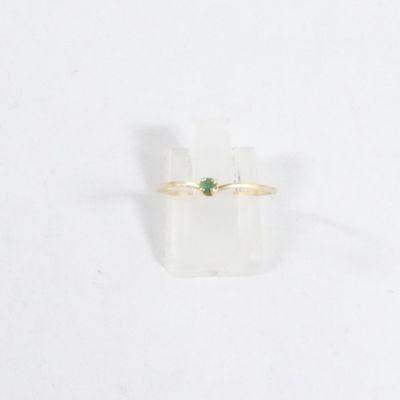 Gros plan sur une bague en or ornée d'une pierre verte