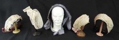trois chapeaux et un porte-chapeaux sur fond noir