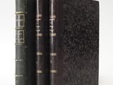 two old books sitting on top of each other on a white surface