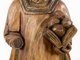 a wooden statue of a man holding a baby