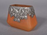 an orange vase with a silver decoration on it