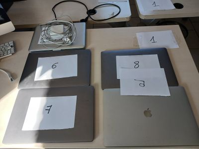 quatre ordinateurs portables posés sur une table, sur lesquels figurent des chiffres