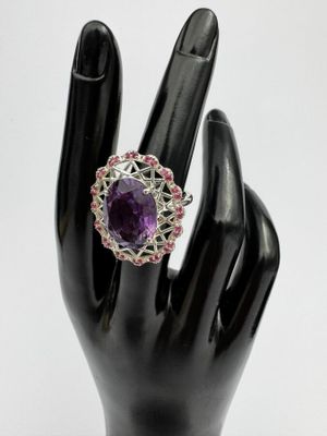 une image représentant une bague ornée d'une pierre violette entourée de pierres roses et blanches