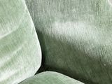 a close up of a green couch with pillows on it
