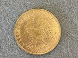 une pièce d'or représentant un coq sur un fond gris