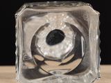 a glass cube with a hole in it on a table