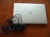 dell laptop with charger and cable plugged to it on a wooden table