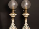 une paire de lampes anciennes en porcelaine posées sur une table en bois devant un mur noir