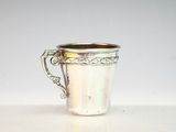 une coupe ancienne en argent munie d'une anse, posée sur un fond blanc