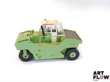 un petit camion jouet vert posé sur une surface blanche