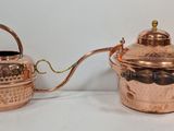 two copper teapots sitting next to each other on a table