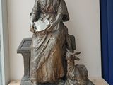 a statue of a woman sitting on a bench with a dog