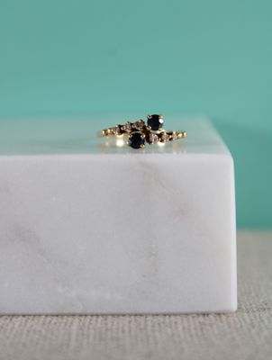 un gros plan d'une bague sertie d'un diamant noir posée sur un bloc de marbre blanc