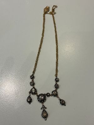 un collier en or orné de pierres noires et blanches sur un fond blanc