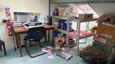 une pièce avec un bureau, des étagères, une chaise et un ordinateur posé dessus