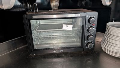 un four grille-pain posé sur un plan de travail, à côté d'une pile d'assiettes