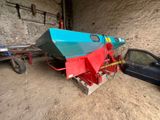 un bateau bleu et rouge dans un garage, à côté d'une voiture noire