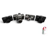four cameras are lined up in a row on a white surface