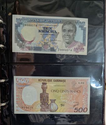 two different bank notes in a binder on a table