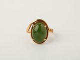 a gold ring with a green jade stone in the center