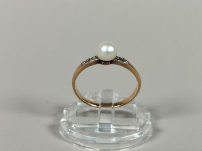 a ring with a pearl on top of a clear stand