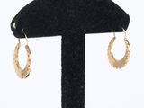 gros plan sur une paire de boucles d'oreilles en or sur un support noir