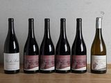 six bouteilles de vin sont alignées sur une table en bois