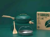 une casserole verte et une cuillère en bois à côté d'une boîte